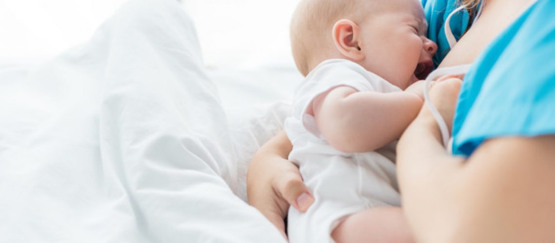 cropped view of mother breastfeeding her baby in hospital